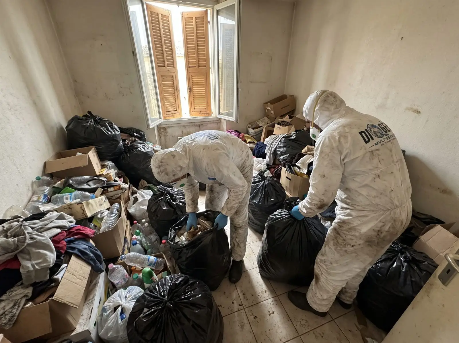 Équipe en tenue de protection dans un logement encombré
